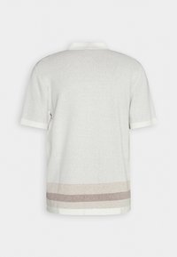 Polo shirt met korte mouwen in lichtgrijze gebreide stof. Dit shirt heeft een witte kraag en een gestreepte zoom in beige en lichtbruin. De stof heeft een textuur en de pasvorm is ontspannen.