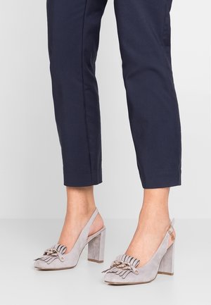 Grey suede block-heeled slingback shoes with a fringed front design and gold-tone chain accent. Smooth texture, open back, and rounded toe.