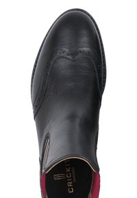 Scarpa in pelle nera con una texture liscia, dettagli broguing lungo i bordi, pannelli laterali elasticizzati e soletta imbottita per il comfort.