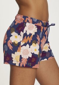 Marineblauwe bloemenshorts met een aansnoerbare taille. Kenmerkt zich door grote roze, witte en paarse bloemen tegen een donkere achtergrond. Zachte katoenen stof.