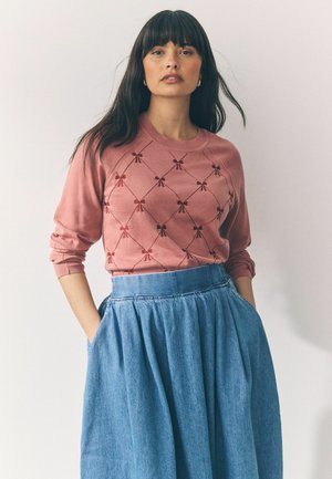 Pink sweater with red bow embroidery, crew neck, and long sleeves. Paired with a flowy light blue denim skirt featuring pockets.