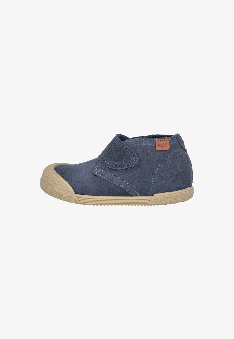 Zapato para niño pequeño de ante azul marino con suela de goma beige y puntera, que cuenta con una correa lateral de velcro y una pequeña etiqueta de logo marrón.
