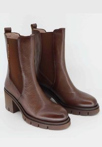 Stivaletti in pelle marrone con tacco a blocco, superficie texturizzata, pannelli laterali elastici e linguette sul retro. Suola in gomma spessa.