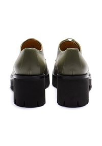 Scarpe in pelle verde dalla forma arrotondata, con un spesso tacco in gomma nera dotato di una superficie texturizzata e dettagli intagliati.