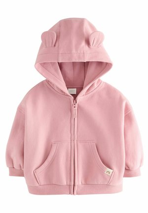 Haut en polaire rose avec fermeture éclair à l'avant, deux poches avant, poignets côtelés et oreilles d'ours sur la capuche. Texture douce avec un design décontracté.