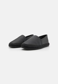 Espadrilles noires à enfiler en cuir lisse, dotées d'une semelle en jute tissée et de logotypes embossés sur le dessus.