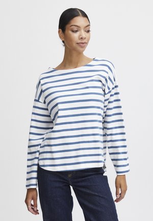 Striped long-sleeve shirt in white with blue horizontal stripes, round neck, soft fabric, relaxed fit, side slits, paired with dark jeans.