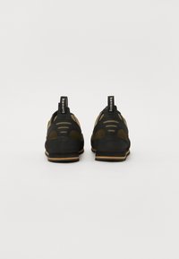 Sort og olivengrøn sneakers med en tekstureret overflade, mesh-paneler og gummisåler. Har trækkroge ved hælen og et robust design.