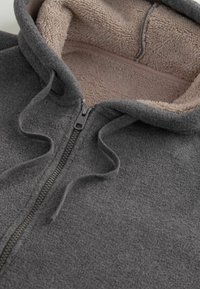 Felpa con cappuccio grigia in pile con rivestimento in peluche beige, zip frontale e cordini. Caratterizzata da una texture morbida e un design del cappuccio curvo.