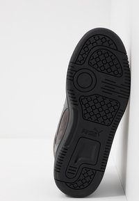 Semelle de chaussure en caoutchouc noir avec un motif de bande de roulement hexagonal, avec une tige en daim gris et des détails de marque. Design profilé avec des bords arrondis.