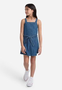 Denim A-line kjole med justerbare stropper, belted midje og plisseret skjørt. Middels blå farge med teksturert stoff.