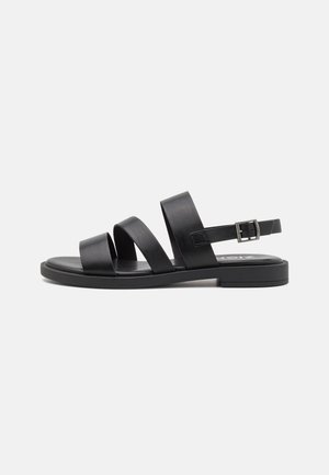 Black leather sandals with three wide straps, adjustable ankle strap, flat sole, and minimal design on a white background.