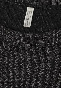 Zwarte gebreide top met een subtiele glans, ronde halslijn en een label met "intimissimi" merk. Textuurstof met een zachte afwerking.