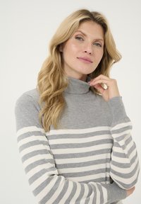 Maglione grigio a collo alto con strisce orizzontali bianche e grigie, texture morbida, design aderente e maniche lunghe.