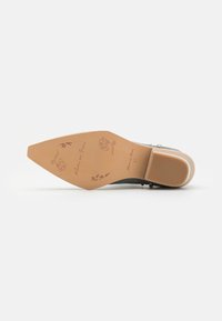 Suela de zapato de tela gris con una suela exterior color marrón. Presenta bocetos florales y texto. Punta redondeada y un ligero tacón con un acabado suave.