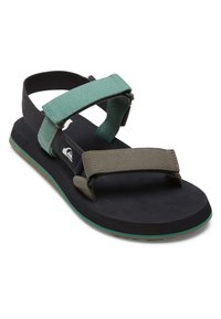 Svart og grønn sandaler med justerbare stropper, teksturert fotseng og en polstret såle med grønn detalj langs kanten.