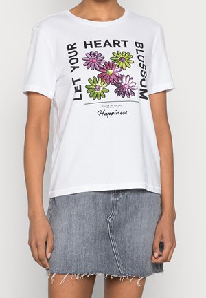 Hvid t-shirt med farverige blomster grafik og tekst "Let your heart blossom", båret med en frynset denim nederdel.