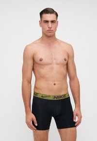 Fekete sport boxeralsó lime zöld mintázattal ellátott derékpánttal, amelyen a Nike logó található, rugalmas, sima anyagból készült.