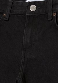 Pantalon en denim noir avec fermeture à bouton métallique, passants pour ceinture et coutures foncées. Il présente un design classique à cinq poches et une texture lisse.