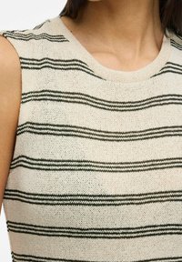 Stickad linne i krämfärgad bas med horisontella gröna ränder, rund halslinje och ärmlös design. Lätt och texturerat material.