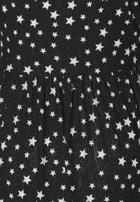 Svart tyg med en rynkig textur, med ett spritt vitt stjärnmönster och en samlad fåll i botten.