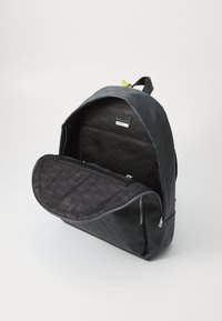 Mochila negra con un exterior texturizado y un patrón de logotipos. Cuenta con un bolsillo frontal con cremallera y un interior espacioso con forro de marca.