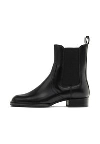 Botte Chelsea en cuir noir avec panneaux élastiques sur les côtés, bout arrondi et petit talon bloc. Texture lisse avec des détails de couture minimalistes.