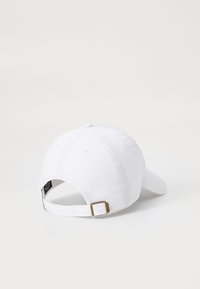 Gorra de algodón blanca con visera curvada, correa ajustable en la parte posterior con hebilla de metal dorado, textura suave y diseño de seis paneles.