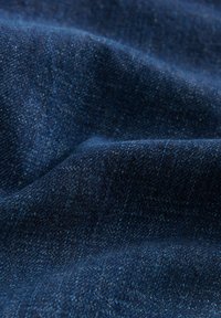 Tummansininen denimpinta, jossa on sileä rakenne ja lieviä sävyvaihteluita. Kestävä kudonta, jossa on kietoutuneita kuituja ja hillitty kiilto.