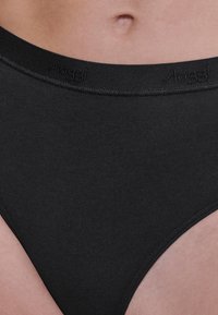 Slip di cotone nero con una consistenza liscia e elastica. Presenta una ampia fascia in elastico in vita e un discreto logo sulla parte superiore.