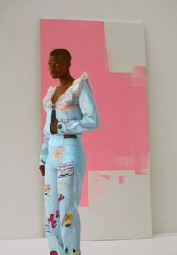 Light blue outfit with ruffled neckline, long sleeves, and patterned pants featuring various graphics. Background is a pink abstract design.