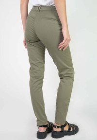 Olive green slim-fit trousers with back pockets, featuring a smooth texture and a simple design; paired with black strappy sandals.