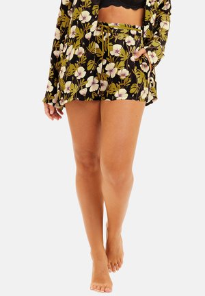 Ensemble de pyjama à manches courtes avec un fond noir, des feuilles vertes et des fleurs blanches ; shorts avec une taille à cordon ajustable.