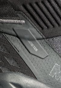 Svart träningsskor med en texturerad ovansida, syntetiska material, förstärkta sömmar och en synlig GORE-TEX-etikett.