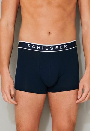 Dunkelblaue Boxershorts aus Jersey mit einem weißen Logo-Bund, auf dem der Text "SCHIESSER" steht. Der Stoff wirkt glatt und hat eine figurbetonte Passform.