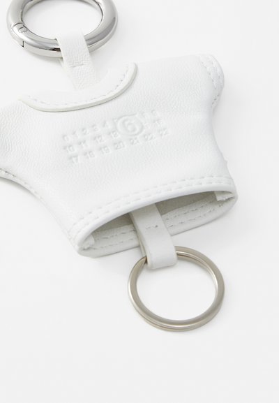 Vit läder nyckelring hållare formad som en skjorta, med präglade siffror, en sydd kant och en metallring för fäste.