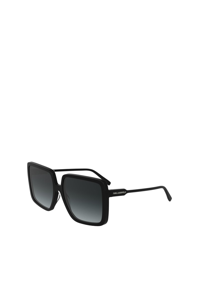 Lunettes de soleil noires surdimensionnées avec une monture carrée, des verres foncés dégradés et des branches fines arborant un accent logo d'un côté.