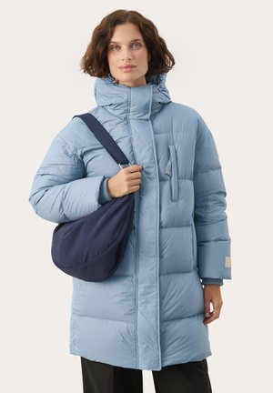 Himmelblaues Daunenjacke mit hohem Kragen, Frontreißverschluss und einer aufgesetzten Tasche. Weicher Stoff, geknöpfte Manschetten, kombiniert mit einer marineblauen Umhängetasche.