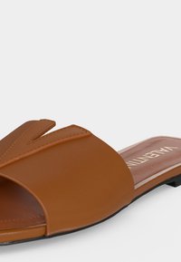 Sandale slide en cuir marron clair avec une bride en V et une semelle noire plate.