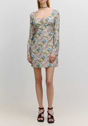 Blümchenmuster Mini-Kleid mit langen Ärmeln in Pastellfarben, mit einem quadratischen Ausschnitt und Zugbanddetail. Kombiniert mit braunen, Riemchen-Absätzen.
