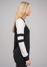 T-shirt à manches longues noir et gris avec col rond, les manches grises étant accentuées de rayures noires, fabriqué en coton doux.