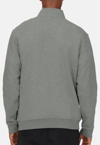 Grijze sweatshirt met een hoge kraag, geribbelde manchetten en zoom, voorzien van een gestructureerd materiaal en een label aan de onderzijde aan de linkerkant.