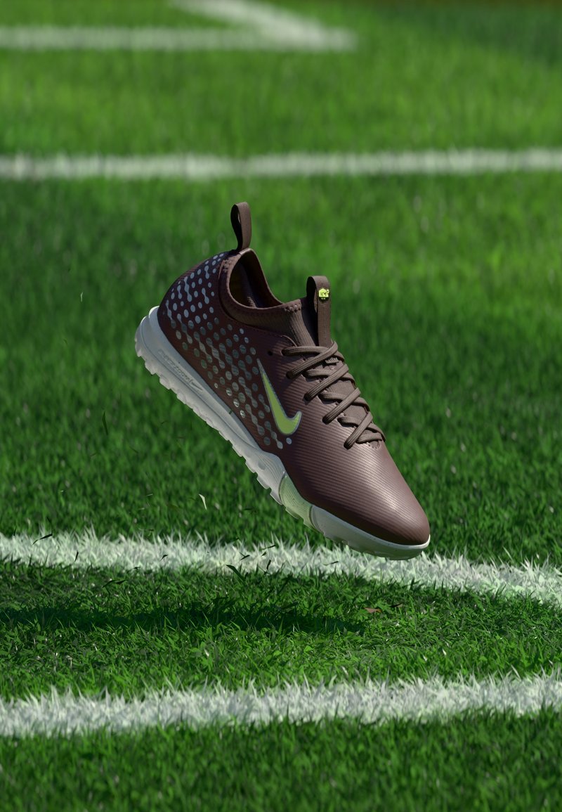 Baskets Nike marron foncé avec semelle blanche et points bleu clair flottant au-dessus d'herbe verte avec des lignes blanches de terrain.