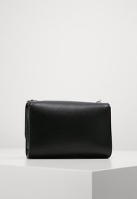 Svart läder rektangulär väska med en slät yta, med dragkedjestängning och minimalistisk design. Accenterad med silverfärgad metall.