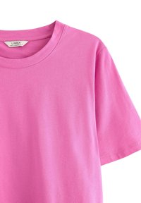 Lyserød bomulds t-shirt med rund halsudskæring og korte ærmer. Glat tekstur og standard pasform. Etiketten inden i halsudskæringen står "Lindex."