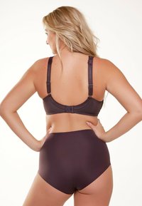 Reggiseno marrone con schiena in pizzo e spalline regolabili, che mostra un tessuto liscio. Slip a vita alta abbinati in marrone con design senza cuciture.