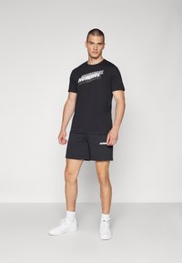 Must have must t-särk mustast puuvillast valge "HUMMEL" logoga, koos mustade lühikestega, millel on sarnane logo, ja valged spordijalatsid. Sujuv tekstuur, iga päev kande disain.
