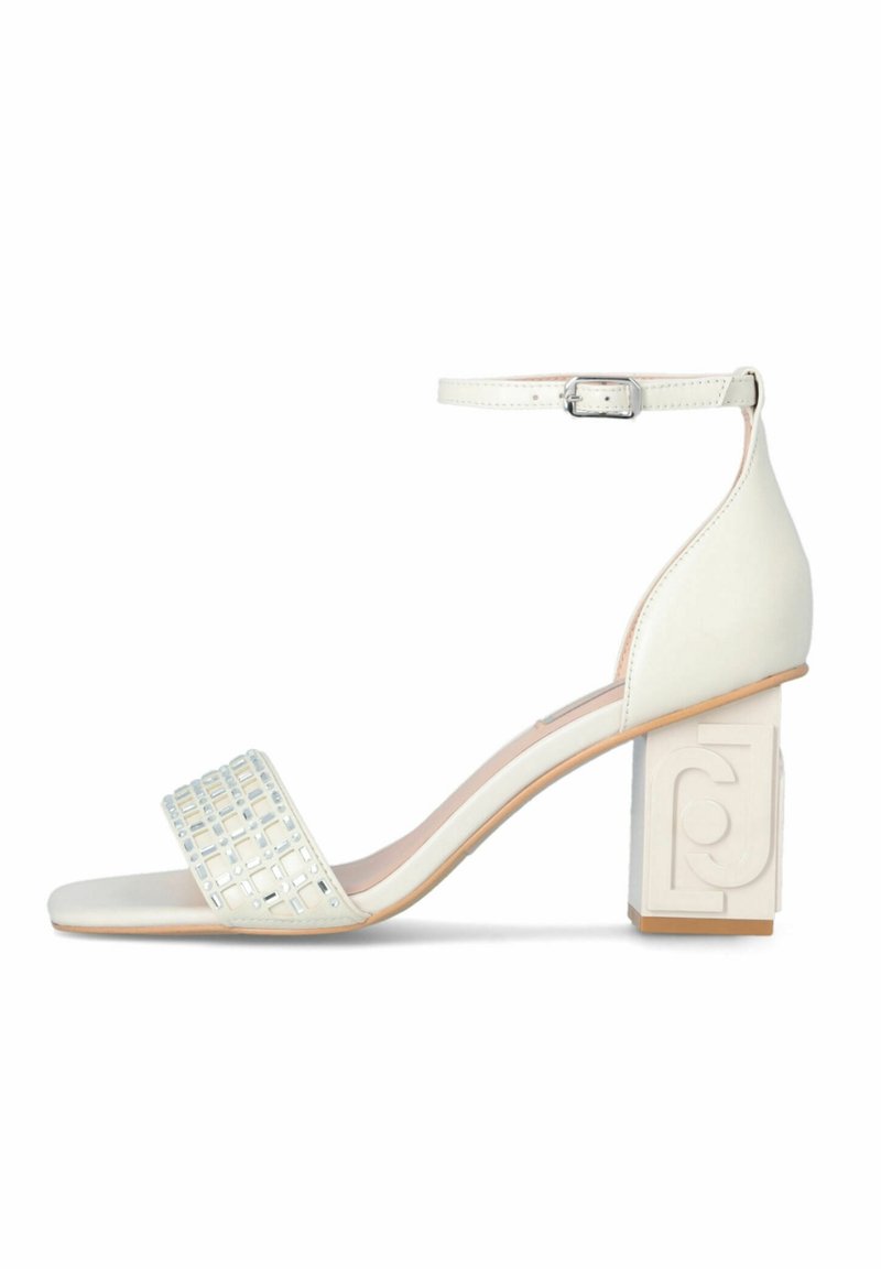 White heeled sandal with a square toe, an ankle strap, and a block heel featuring a textured geometric pattern on the front strap.