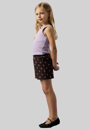 Un débardeur lilas, un short marron avec un motif de pois clairs, et des ballerines noires. La tenue présente une coupe décontractée et un design simple.