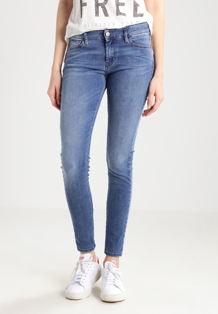 Modré džíny skinny s vysokým pasem, jemným opotřebením a hladkou texturou, doplněné bílými teniskami.